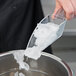 A person using a Cal-Mil polycarbonate scoop to put ice in a bowl.
