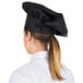 A woman wearing a black Choice customizable chef hat.