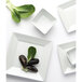 A close-up of a Tuxton TuxTrendz Santorini bright white square china plate with a green leaf and a black mussel on it.