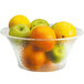 A clear Cal-Mil acrylic bowl filled with oranges, lemons, and apples.
