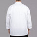 The back of a man wearing a white Chef Revival long sleeve chef jacket with Chef logo buttons.
