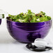A close-up of a Vollrath passion purple beehive serving bowl filled with salad with a spoon.