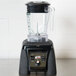 A Waring commercial blender with a clear jar and black lid on a counter.