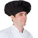 A man wearing a black Chef Revival chef hat with an adjustable head band.