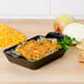 A Lodge mini cast iron casserole dish with cheese and onions on top.