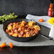 A Lodge cast iron skillet filled with food including corn and sausage on a table.