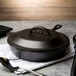 A Lodge pre-seasoned black cast iron skillet on a table with a napkin and a spoon.