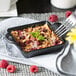 A Lodge mini cast iron square casserole dish with raspberries and oatmeal with a fork.