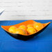 A GET Brasilia orange and black melamine bowl filled with oranges on a table.