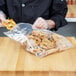 A person in a chef's uniform using an LK Packaging heavy weight seal top plastic bag to hold pretzels.