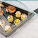 A black Cambro market tray on a counter with cupcakes, pastries, and muffins.