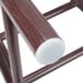 A close up of a wooden chair with a white Lancaster Table & Seating chair glide.
