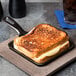 A grilled cheese sandwich cooking in a Lodge mini cast iron skillet.