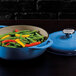 A Lodge Caribbean Blue Enameled Cast Iron Dutch Oven with a lid full of green beans and yellow peppers.