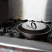 A Lodge cast iron skillet with a lid on a stove top.