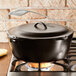 A Lodge black cast iron dutch oven with a lid on a stove.