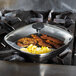 A Lodge square tempered glass cover on a skillet with eggs and bacon cooking on a stove.