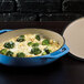 A Lodge Caribbean blue enameled cast iron casserole dish with broccoli and cheese.