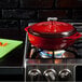 A Lodge Island Spice Red enameled cast iron dutch oven on a stove.