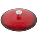 A Lodge Island Spice Red enameled cast iron casserole dish with a white lid on a table in a home kitchen.