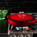 A Lodge Island Spice Red Enameled Cast Iron Casserole dish with lid on a stove.