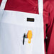 A person wearing a white Chef Revival bib apron with a pen and yellow tool in the pocket.