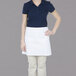 A woman wearing a white Chef Revival waist apron.