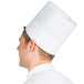 A person wearing a Chef Revival pinstripe chef hat with adhesive closure.