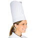 A woman wearing a Chef Revival pleated flair style chef hat.