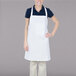 A woman wearing a white Chef Revival bib apron with a pocket.