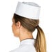 A woman wearing a white Chef Revival paper overseas cap with a ponytail.