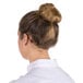 The back of a woman with brunette hair in a bun wearing a hairnet.