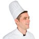A man wearing a Chef Revival disposable non-woven chef hat with a vented top.