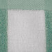 A close up of a mint green and white striped Oxford pool towel.