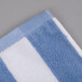 A close up of a blue and white striped Oxford cabana pool towel.