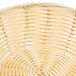 A close up of a Thunder Group natural rattan basket with an oval shape.