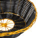 A close up of a Thunder Group black and gold rattan basket with a handle.