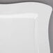 A close up of a white Fineline square plastic plate with a curved edge.