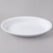 A Fineline white plastic deep oval bowl on a gray surface.