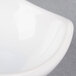 An American Metalcraft white ceramic sauce cup with a curved edge on a white surface.