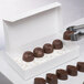 A white 1-piece candy box filled with chocolate candy.