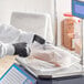 A person wearing black gloves weighing a piece of meat in a plastic deli bag.