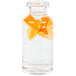 A Libbey glass water bottle filled with water and orange slices on a table.