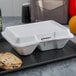 A white styrofoam container with two compartments of food and a cookie on a tray.