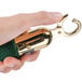A hand holding a green and gold Aarco stanchion rope end.