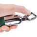A hand holding a metal hook with a green handle.