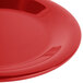 A close-up of a red Carlisle Sierrus melamine pie plate with a shiny surface.