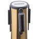 A brass Aarco crowd control stanchion with a black and blue metal cylinder.