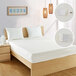 A white Bargoose vinyl mattress cover on a bed with white pillows and a wooden frame.