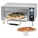 A Waring countertop pizza oven with a pizza baking inside.